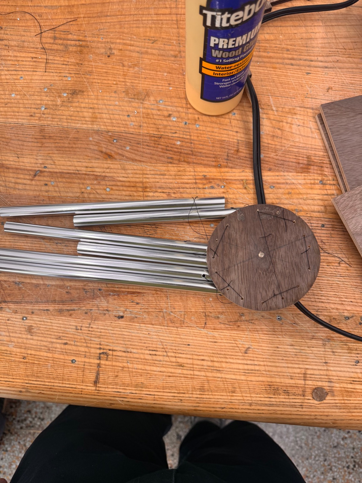 Chime tubes strung to a drilled wooden disc on the workbench